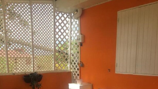 Une terrasse ensoleillée avec un canapé, des fauteuils et une table basse.