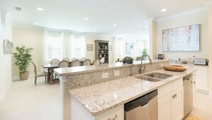 A modern kitchen with granite countertops, a built-in dishwasher, and a dining area with a table and chairs. - Fabulous Disney Vacation Home - 5 Minutes From Disney (Kissimmee)