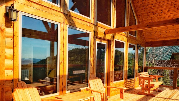 A wooden deck with wooden chairs and tables, large windows, and a view of the outdoors. - Gorgeous Smoky Mountain Views! Amazing Views Near Pigeon Forge & Gatlinburg! (Sevierville)