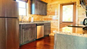 A modern kitchen with wooden walls, stainless steel appliances, and a granite countertop. - Gorgeous Smoky Mountain Views! Amazing Views Near Pigeon Forge & Gatlinburg! (Sevierville)