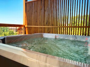 Un jacuzzi con cerramiento de madera y vista a un edificio al fondo.