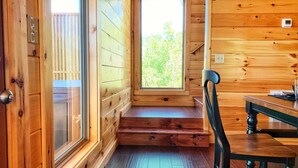 A wooden cabin interior with a window, a table, and a chair. - Gorgeous Smoky Mountain Views! Amazing Views Near Pigeon Forge & Gatlinburg! (Sevierville)