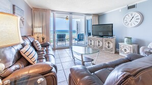 A living room with leather sofas, a glass coffee table, a television, and a balcony with a view of the ocean. - 🌅 Free Seasonal Beach Chairs • Gulf Views • Shoreline 3073 (Destin)