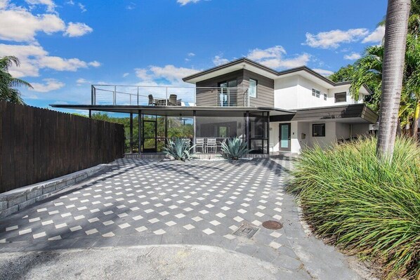 A modern two-story house with a covered patio area, a wooden fence, and tropical plants. - Mid-Centrury Oasis | 1 Block to Ft Lauderdale Beach (Fort Lauderdale)