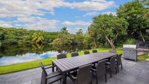 Un patio exterior con mesa y sillas, una parrilla y un estanque.