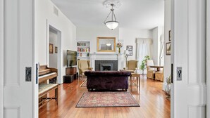 A living room with a fireplace, a piano, a sofa, and a chandelier. - Historic Silverton Home 5 BR, 6 Bath.  Ask about 6th & 7th bedroom add-ons. (Silverton)