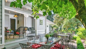 A covered patio with outdoor furniture, a glass table, and a hanging light fixture. - Historic Silverton Home 5 BR, 6 Bath.  Ask about 6th & 7th bedroom add-ons. (Silverton)