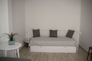 Une petite chambre blanche avec un lit simple et un bureau escamotable.
