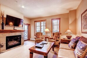 Cozy living room with a fireplace, comfortable seating, and a television, offering a warm and inviting atmosphere.