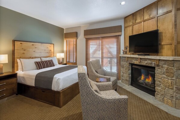 Ein Hotelzimmer mit Bett, Sessel, Kamin und Fernseher.