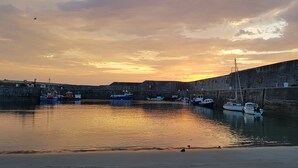Um porto com barcos atracados em um cais de pedra, cercado por um muro de pedra.