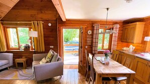 Interior acolhedor de uma cabana com uma mesa de jantar de madeira, um sofá e uma cozinha.