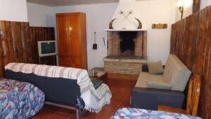 Ein gemütliches Zimmer mit Bett, Sofa, Fernseher und Kamin.