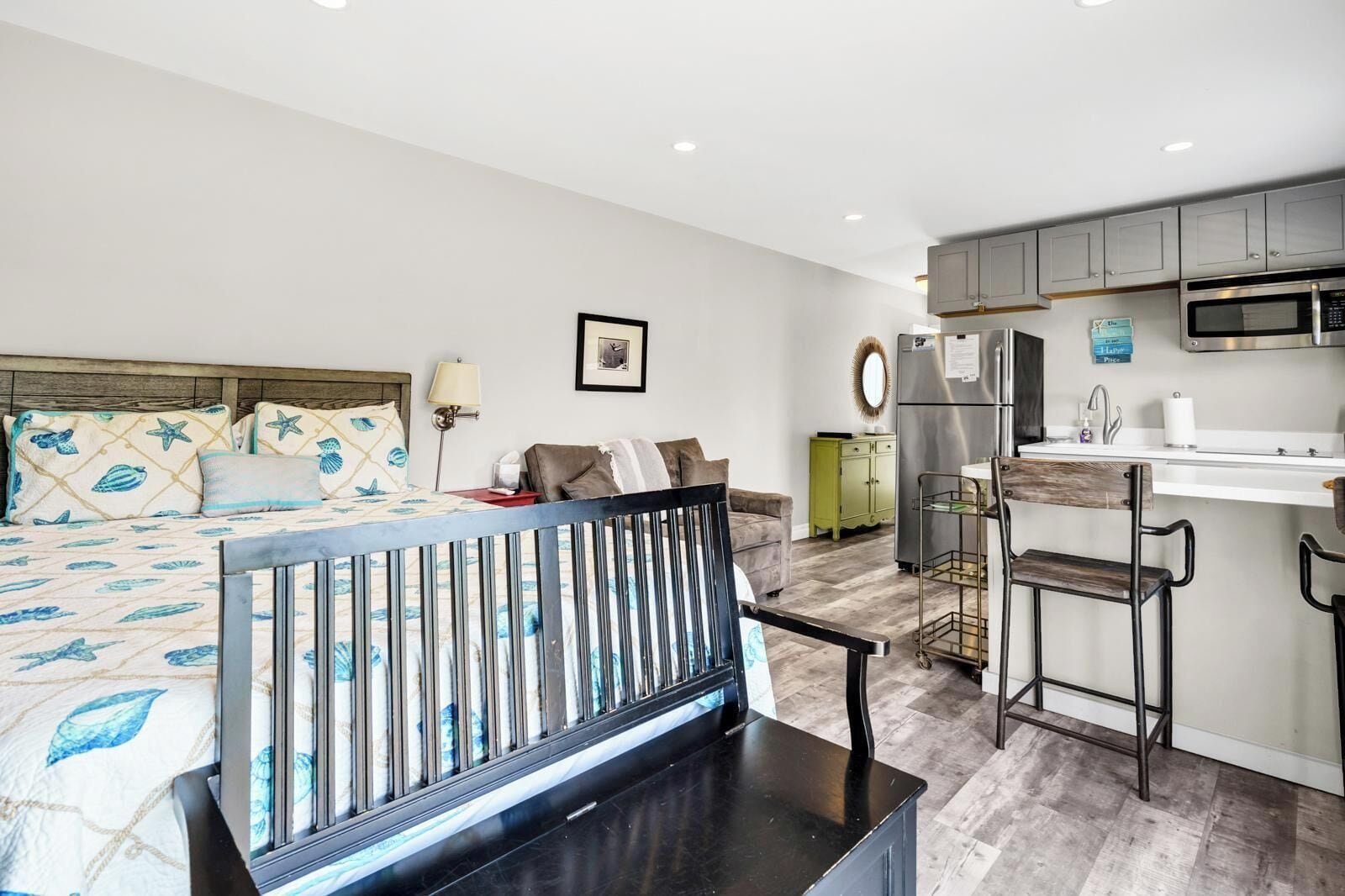 Une chambre d’hôtel compacte comprenant un lit, une banquette, un coin cuisine et un petit espace repas.