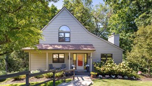 A single-story house with a front porch, a small garden with flowers, and a wooden fence.