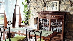 Een rustieke eethoek met een houten tafel en stoelen, een stenen muur en een hangende plant.