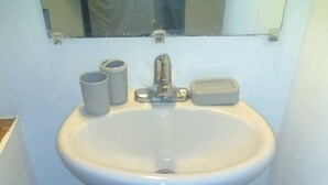 A bathroom with a white sink, a mirror above it, and a blue bath mat on the floor.