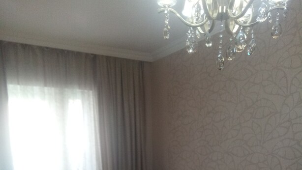 A bedroom with a bed, a chandelier, and a window with curtains. - Квартира центр города (Baku)