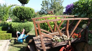 Un giardino con una panchina di legno, una scultura blu e fioriere.