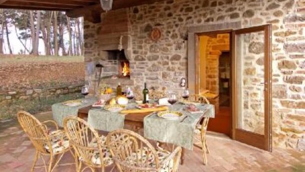 Un'accogliente interno in pietra rustica con un tavolo da pranzo apparecchiato per un pasto, circondato da sedie in vimini.