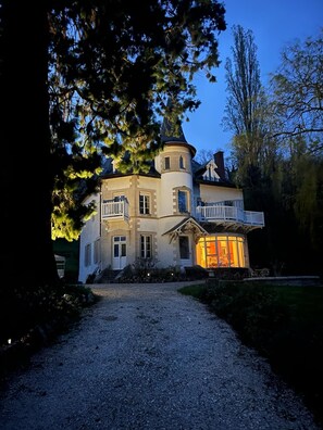 A large, multi-story house with a prominent tower, a balcony, and a well-lit interior. - LA BULNIERE QUIET, LUXURIOUS BELLE ÉPOQUE PROPERTY (Mont-Saint-Jean)