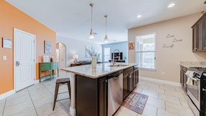 A modern kitchen with a central island, built-in appliances, and a dining area.