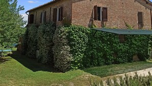 A rustic brick building with a sloped roof, surrounded by a well-maintained garden and a clear blue sky. - Independent flat 2 pax downstairs, in Villa, Siena View, Pool A/C, organic Farm (Siena)