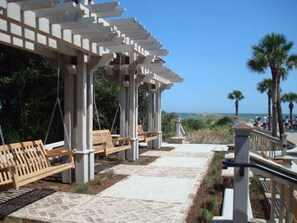 A covered outdoor seating area with benches and a pergola structure. - Sunny Days & Coastal Stays 2BR Villa in Coligny Be (Hilton Head Island)