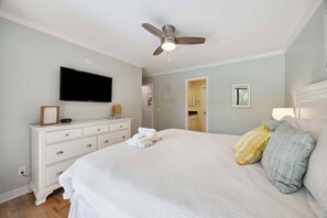 A bedroom with a bed, a dresser, a television, and a ceiling fan. - Sunny Days & Coastal Stays 2BR Villa in Coligny Be (Hilton Head Island)