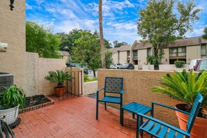 A patio with a brick floor, a metal gate, and a chair.