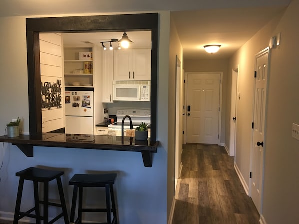 Kitchen features white cabinetry, stainless steel appliances, and a large mirror above a countertop.