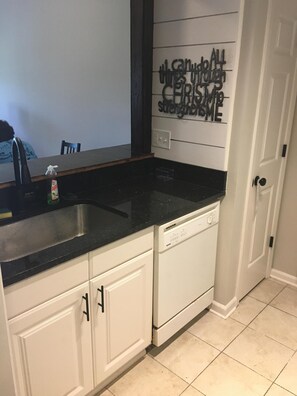 Kitchen features a sink, dishwasher, and decorative wall with inspirational phrase.