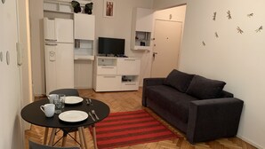 Un espacio habitable compacto con comedor, kitchenette y sofá.