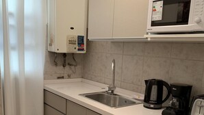 Una cocina compacta equipada con lavadora, microondas, cafetera y lavaplatos.