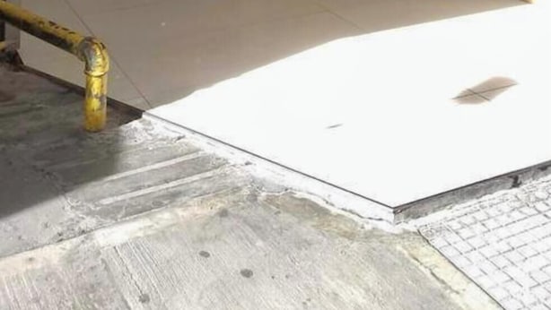 Una entrada moderna con puertas de vidrio, una pared de madera y un respiradero de metal.