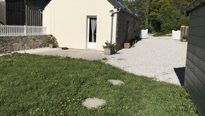 Una casa pequeña de una sola planta con fachada blanca y cimientos de piedra.