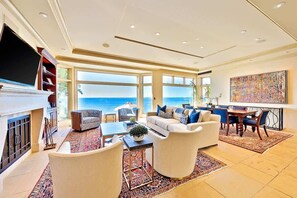 Un amplio salón con un ventanal grande que da al mar, una chimenea y un comedor con vistas.