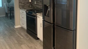 A modern kitchen with a black refrigerator, white cabinets, and a tiled backsplash. - Entire Single Family Home with Pool.  Old Town Scottsdale! License #2037712 (Scottsdale)