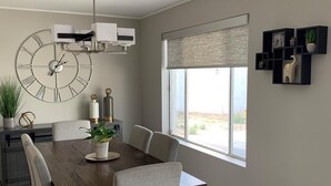 A dining area with a wooden table, four chairs, a large wall clock, and a window with a view. - Entire Single Family Home with Pool.  Old Town Scottsdale! License #2037712 (Scottsdale)