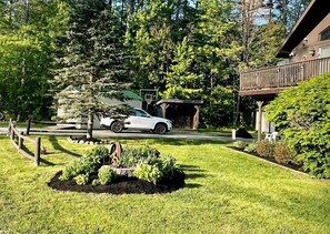 A residential property with a well-maintained lawn, a basketball hoop, and a car parked in the driveway.