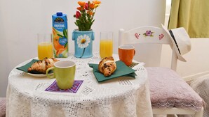 A breakfast setup with croissants, juice, and a flower vase on a white table. - Apartments Mila - Studio apartment (Dubrovnik)