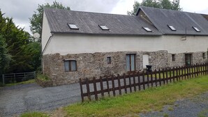 Un bâtiment en pierre et de couleur blanche, doté de nombreuses fenêtres et d’un toit en pente.