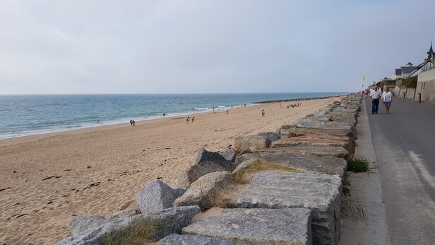 Une plage bordée d’un muret et dotée d’une promenade dallée.