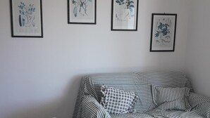 A dining area with a table, chairs, and two yellow cups. There is a striped sofa against the wall and three framed botanical prints above it. - House 20 meters from the sea! (Fossacesia Marina)
