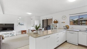 Une cuisine moderne avec des meubles blancs, un plan de travail en bois et un lave-vaisselle encastré.