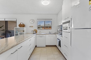 A modern kitchen with white cabinetry, a built-in dishwasher, and a stainless steel refrigerator.