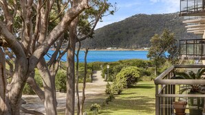 Une vue sur la côte, avec un sentier menant à une plage, le tout bordé d’arbres et avec un bâtiment doté d’un balcon.