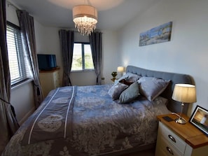Une chambre à coucher avec un lit, des lampes de chevet, une télévision et un tableau au mur.