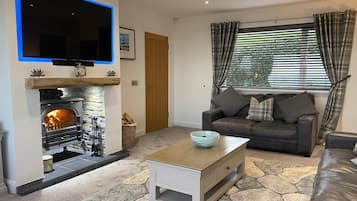 A living room with a fireplace, a sofa, a coffee table, and a television mounted on the wall.