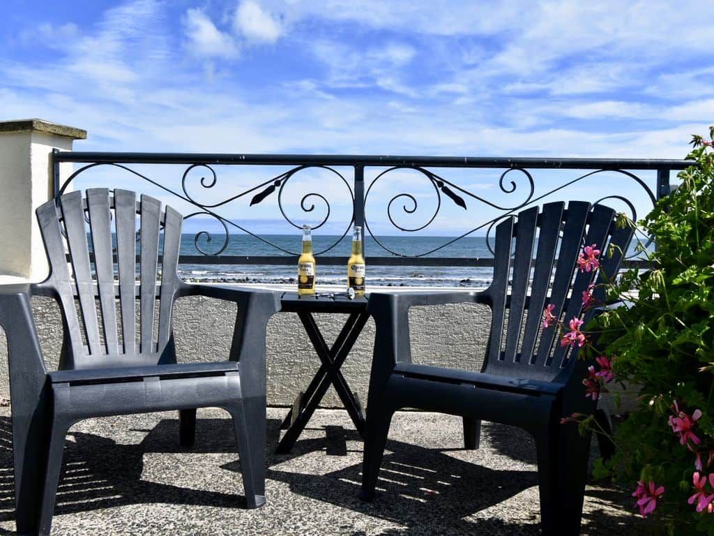 En terrasse ved havet med to stole og et bord, med udsigt over oceanet.